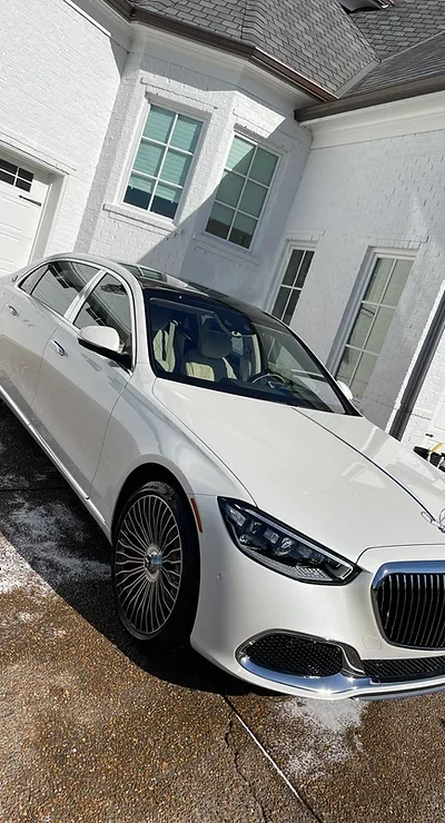 White luxury sedan on wet driveway in front of modern white house; Cody-X service. Cody-X Pressure Washing