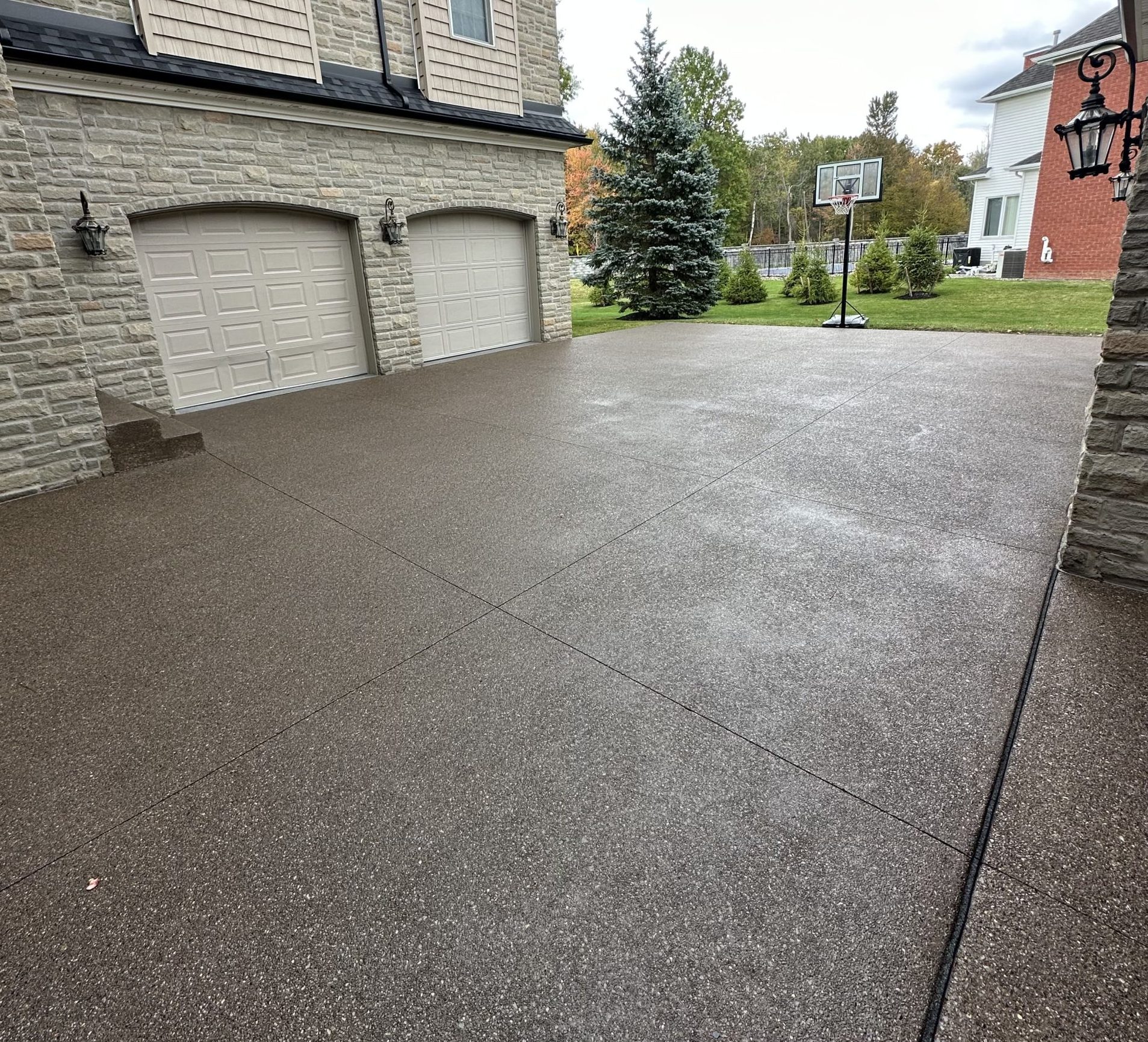 Photo Dec 18 2024, 8 45 16 AM Wet concrete driveway, stone house, double garage, basketball hoop Cody X Pressure Washing