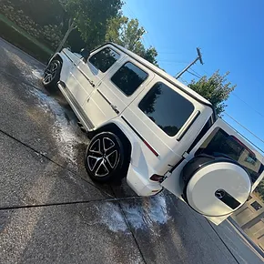 ef9505_2c2aa71b421a454ba33cf15b36b47449mv2.webp A white SUV with its rear door open is being washed on a driveway Cody X Pressure Washing