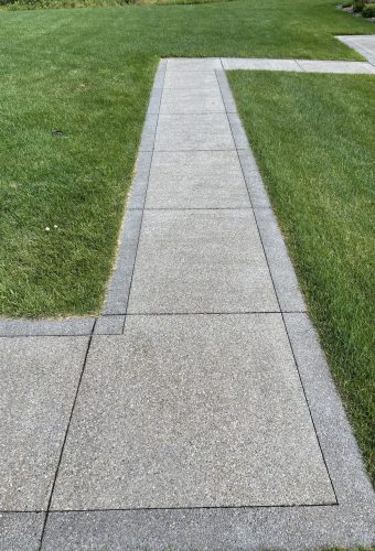 Photo Aug 10 2022, 10 09 05 AM Concrete sidewalk with sharp turns, bordered by vibrant green grass. Cody-X Pressure Washing