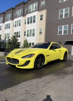 Photo Sep 14 2022, 4 20 44 PM A yellow Maserati on wet pavement in front of a modern apartment building. Cody-X Pressure Washing