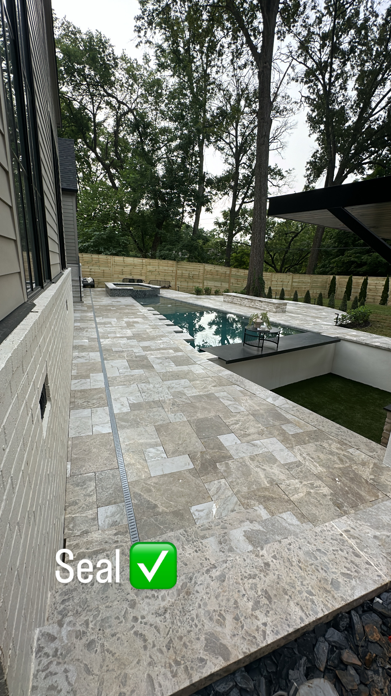 642AD092-F6A8-48A9-B384-9EA26D8D8437 Sealed stone patio near pool, trees, wood fence; “Seal” text with green checkmark Cody X Pressure Washing