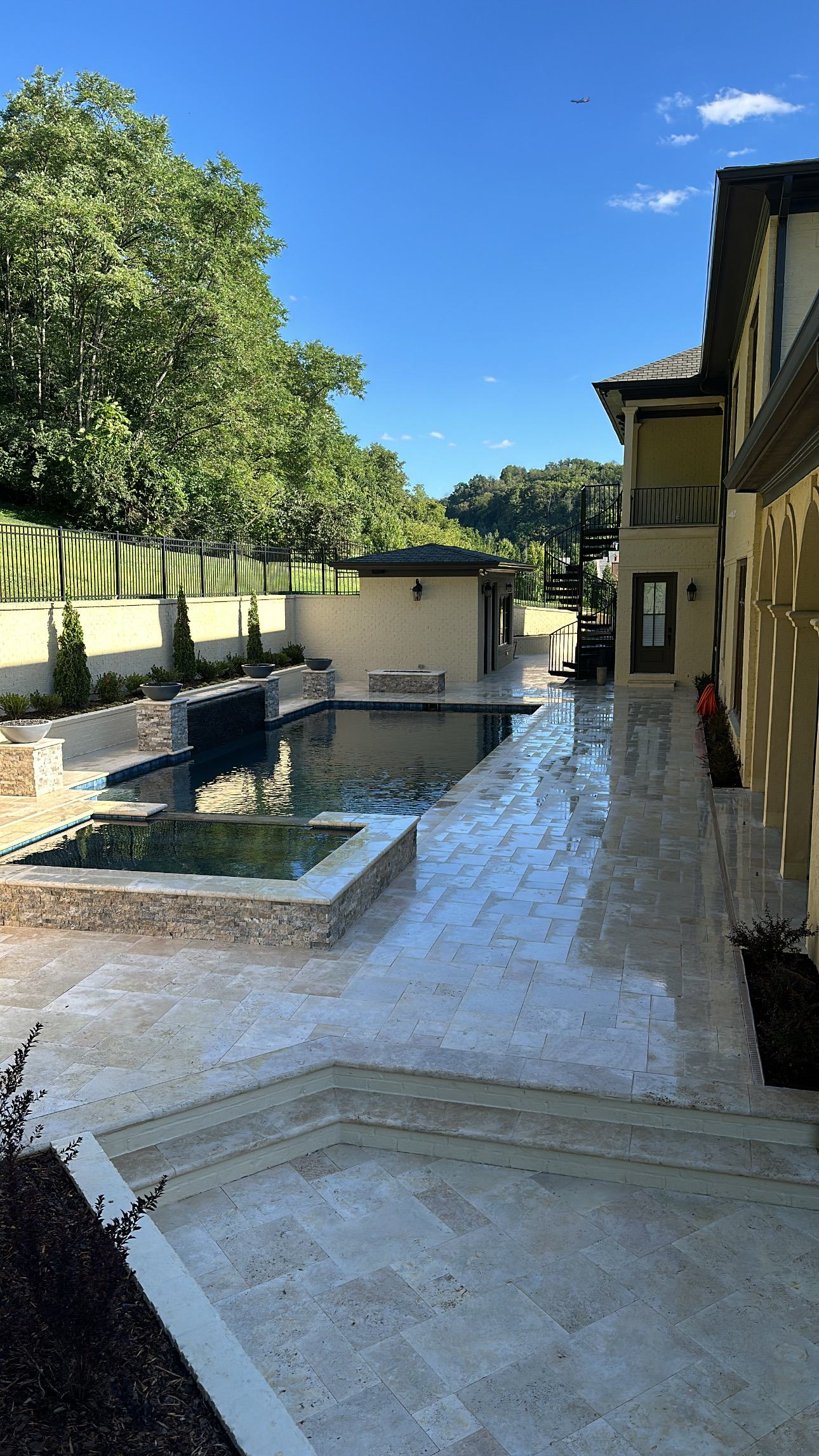 E5E96A6F-EF75-477D-9361-F029FE83CDD2 Modern backyard with pool, hot tub, stone patio, and lush trees Cody X Pressure Washing