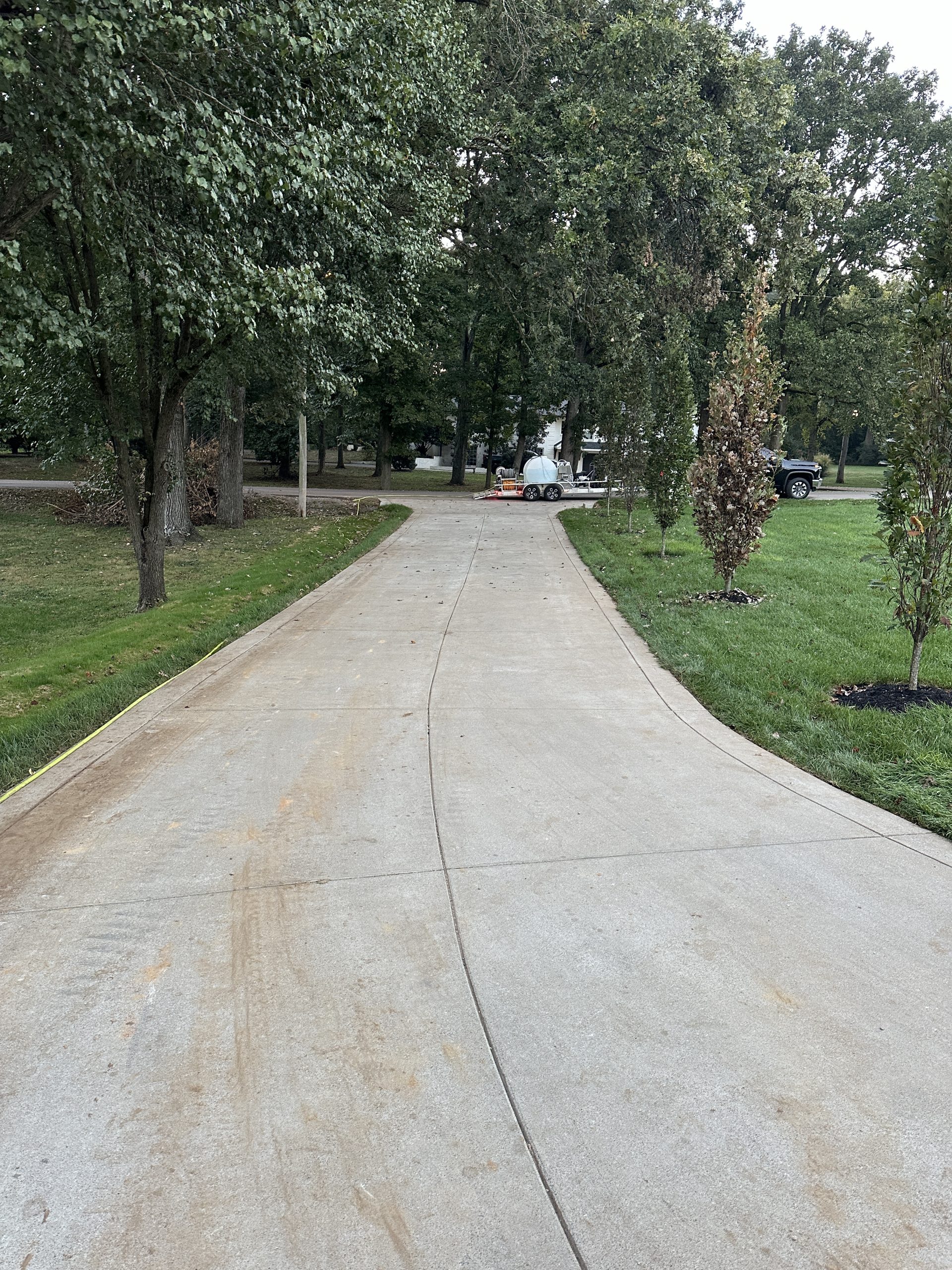 IMG_0659 Fresh concrete driveway curves through grassy yard with trees and a truck Cody X Pressure Washing