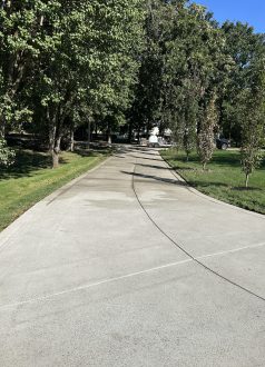 IMG_0669 Concrete driveway with green grass, shade trees, and parked vehicles. Cody-X Pressure Washing