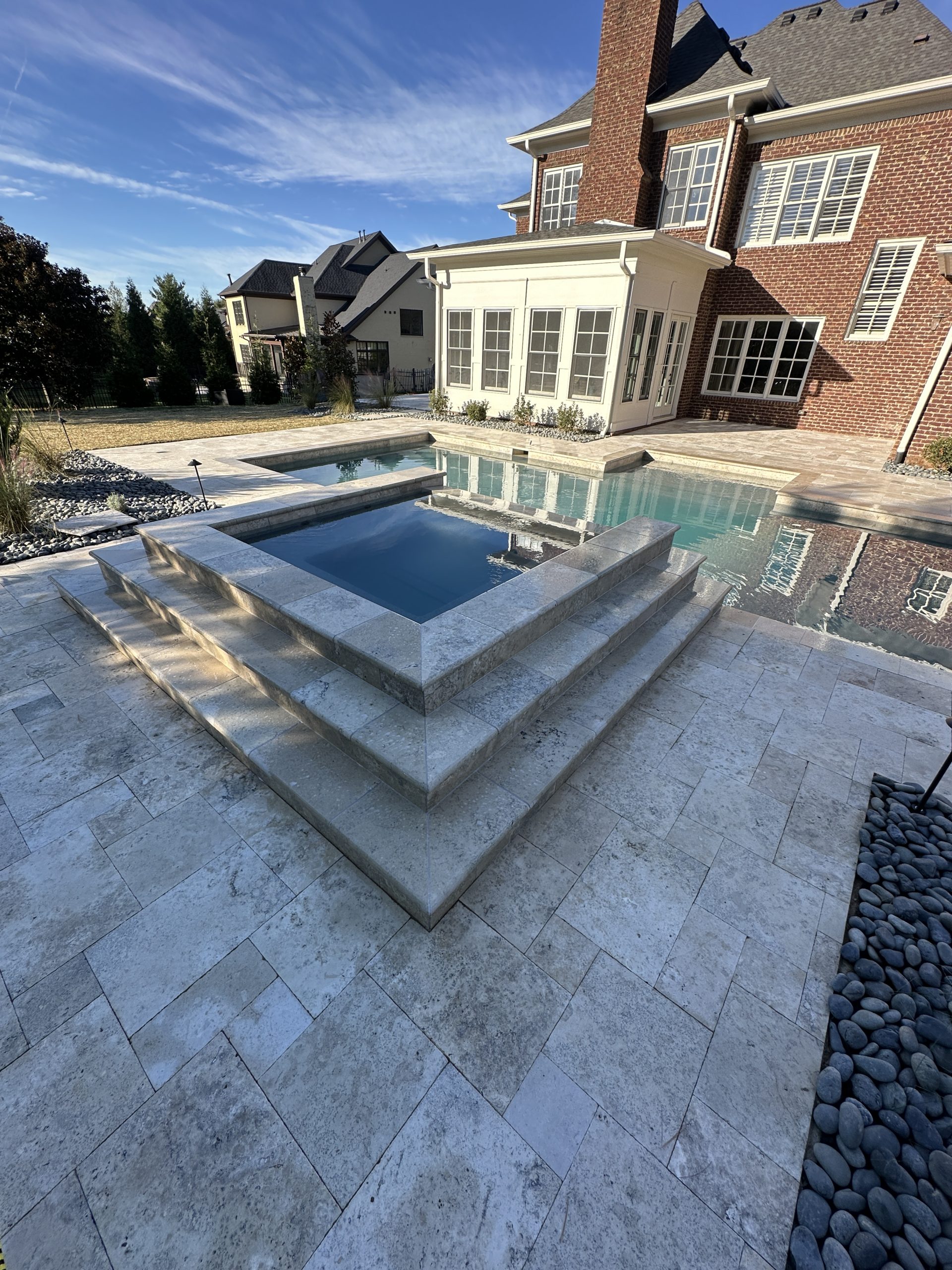 IMG_0818 A square hot tub and pool in a paved backyard by a large brick house Cody X Pressure Washing