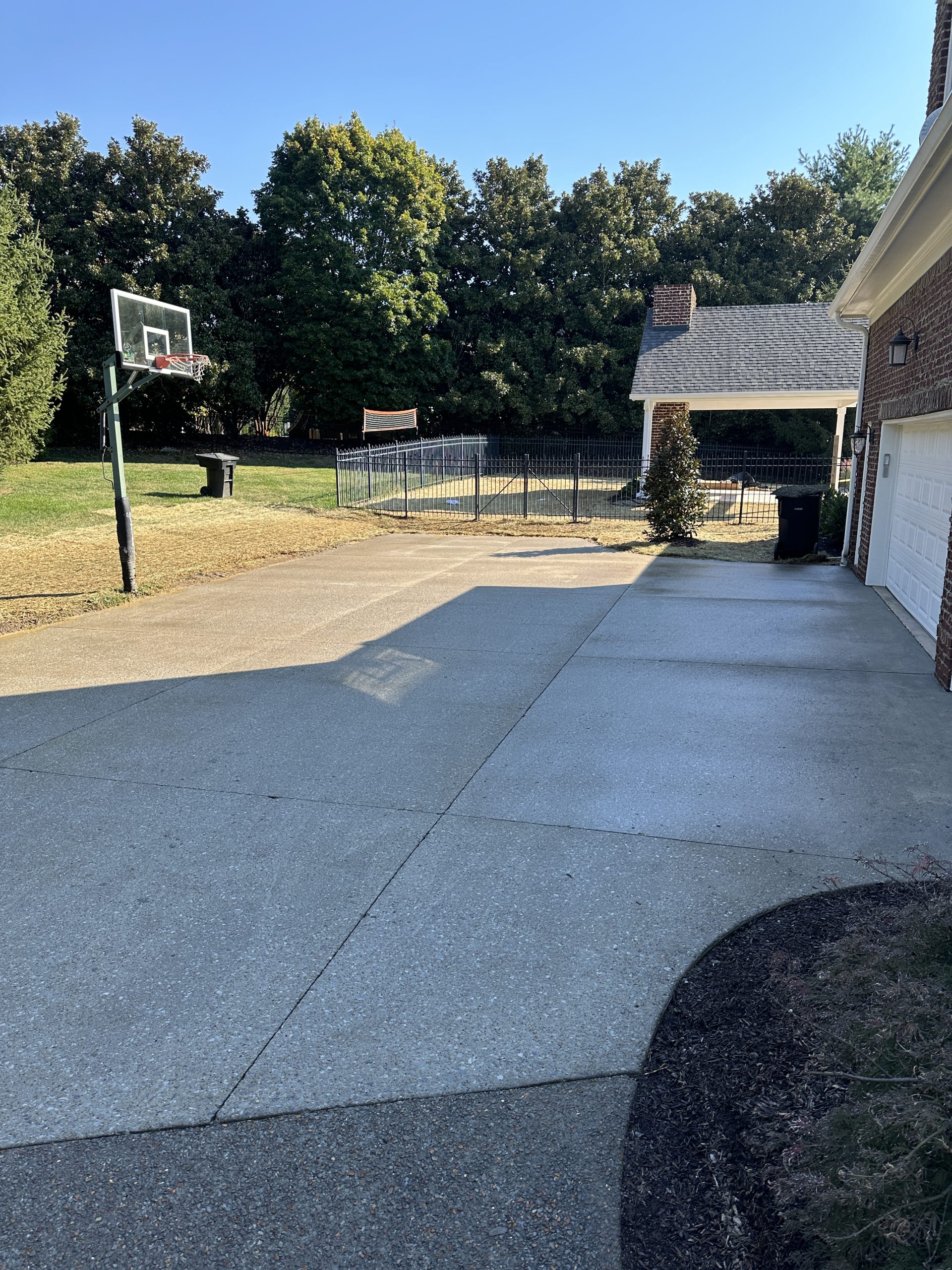 IMG_0836 Clean concrete driveway with basketball hoop beside brick house and yard Cody X Pressure Washing