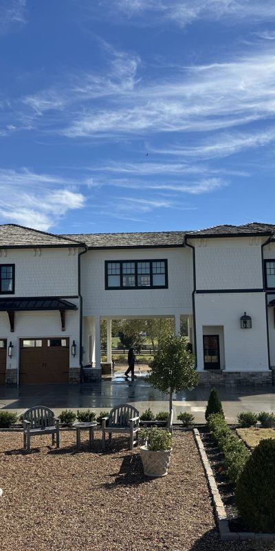 White modern house with three wooden garages, landscaped yard, sunny day. Cody-X Pressure Washing