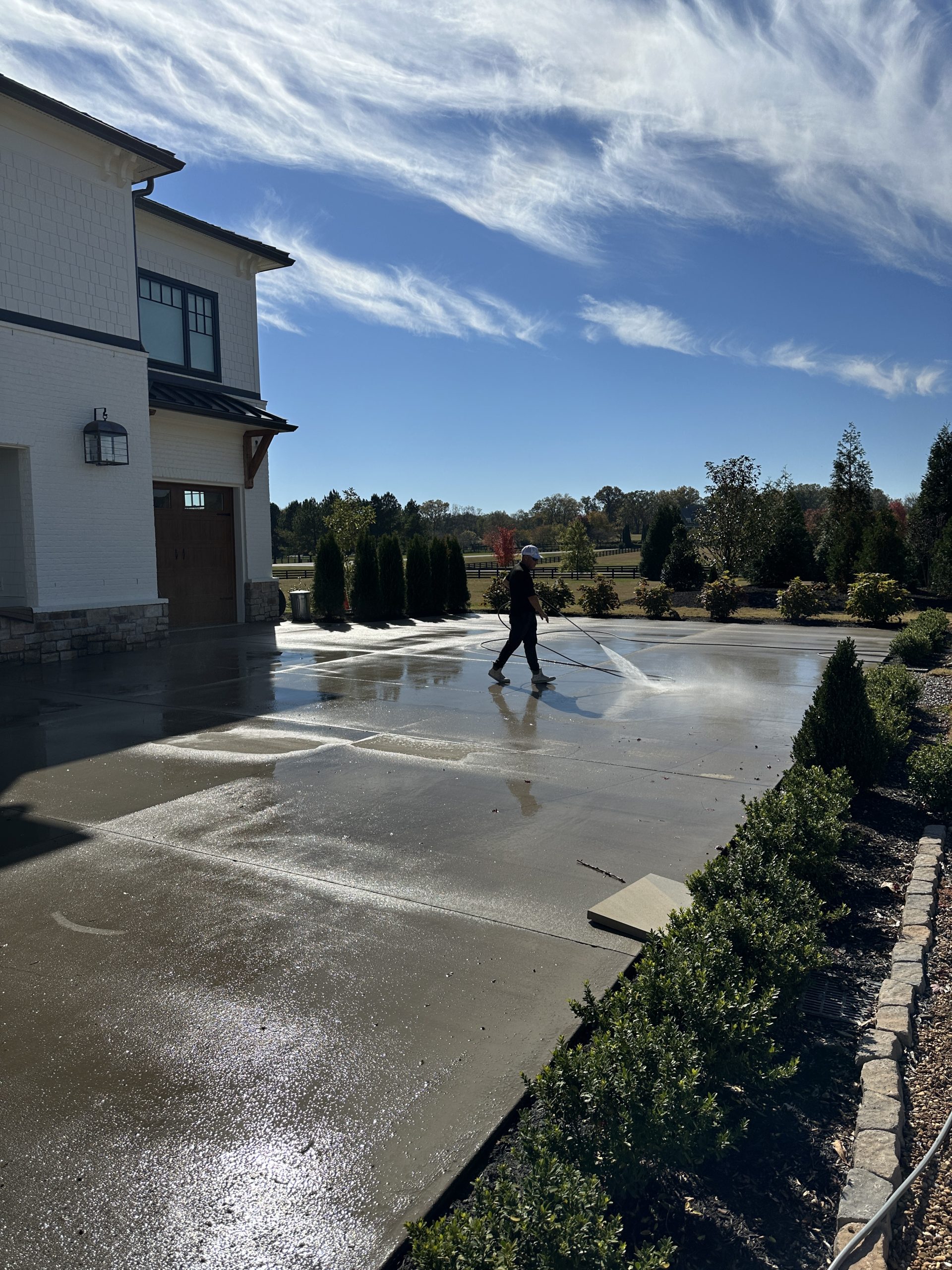 IMG_1117 Person pressure washes driveway at modern house for Cody X service Cody X Pressure Washing