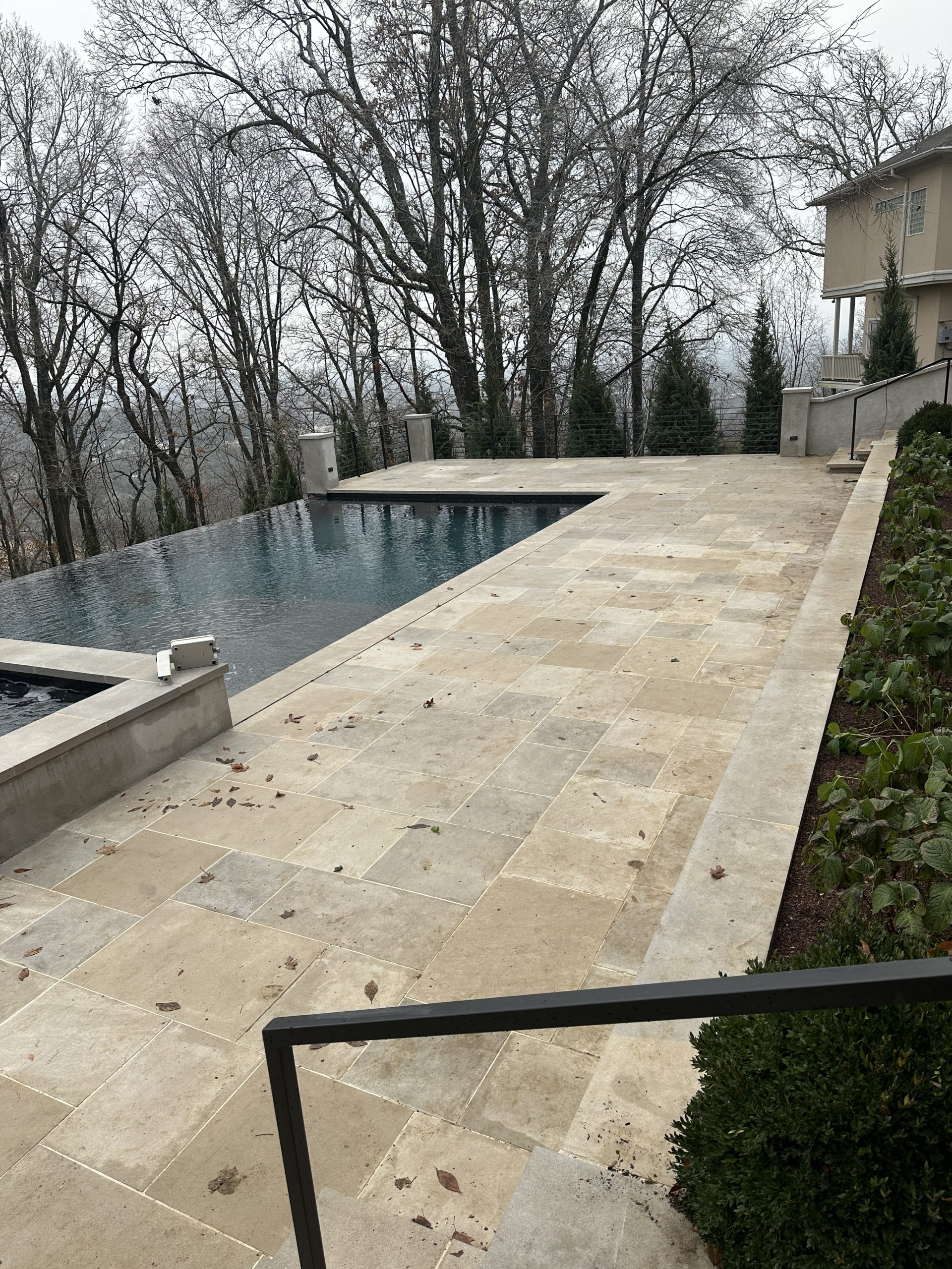 IMG_1879 Rectangular infinity pool with stone tile deck, trees, and modern house Cody X Pressure Washing