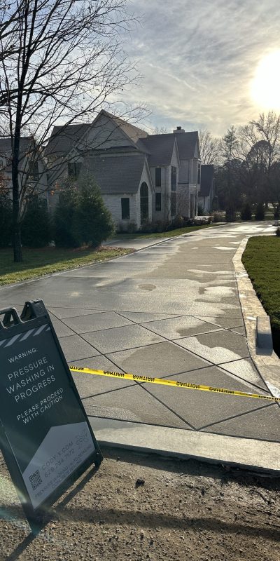 Cody-X pressure washing a home's wet driveway; caution tape blocks access. Cody-X Pressure Washing