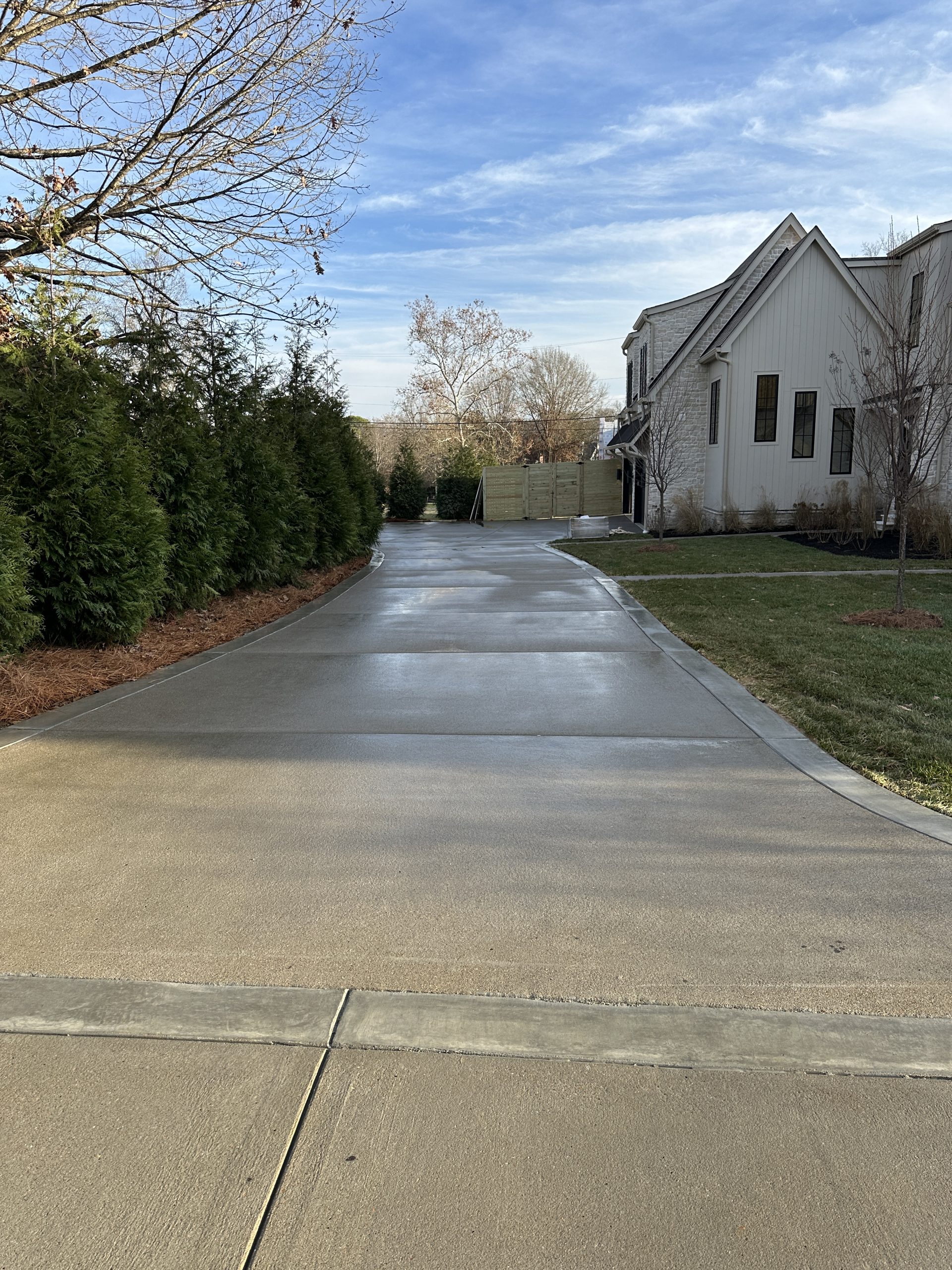IMG_1992 2 Clean driveway leads to white house, green lawn, and trees under clouds Cody X Pressure Washing