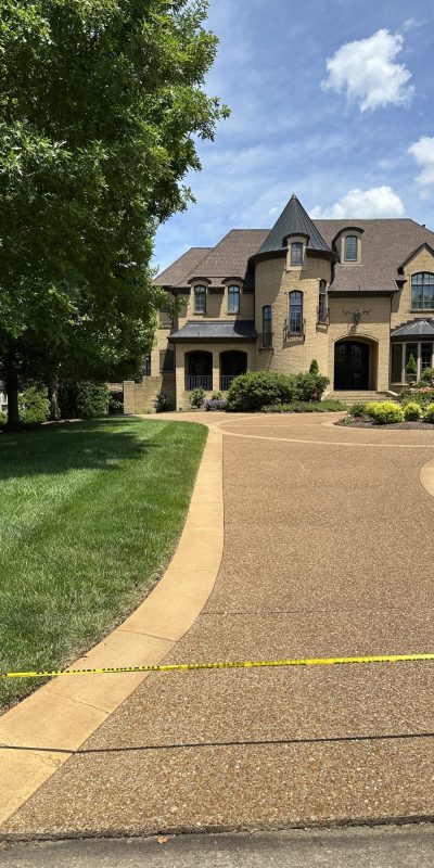 Large brick house, manicured lawn, blocked driveway with caution tape. Cody-X Pressure Washing