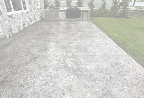 concrete-seal-bg Textured concrete patio by stone wall, grill, and lawn with shrubs. Cody-X Pressure Washing