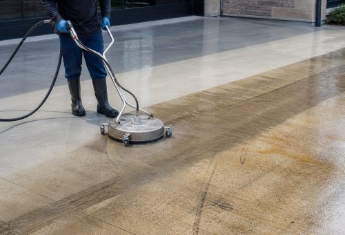 ChatGPT Image May 4, 2026, 05_39_55 PM A person pressure washes a large, dirty concrete driveway for Cody-X. Cody-X Pressure Washing