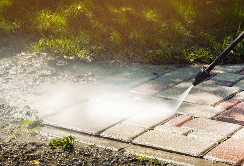 cody-pw-hero A person uses a pressure washer on an outdoor walkway near grass. Cody-X service. Cody-X Pressure Washing