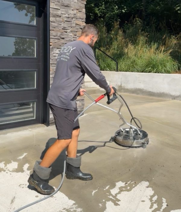homepage-1-878x1024 Person pressure washes outdoor concrete in boots near stone and glass building Cody X Pressure Washing